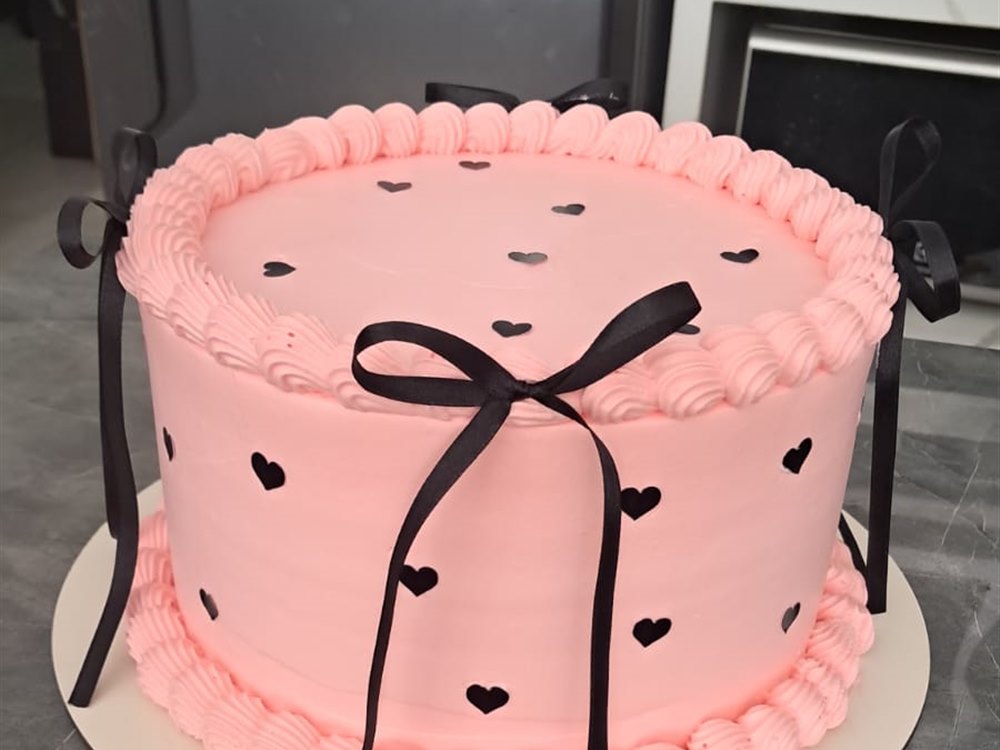 Bolo rosa com laço preto e corações
