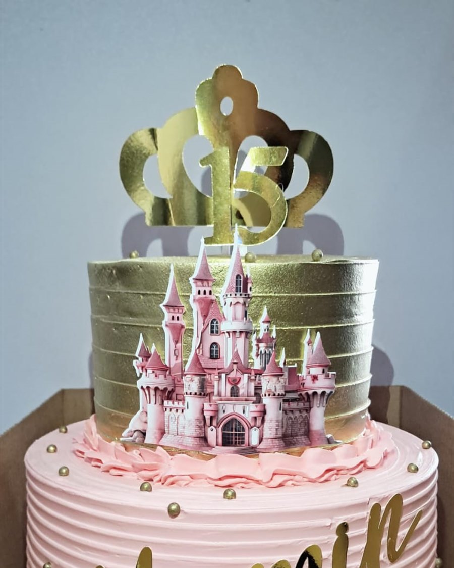 Bolo dourado e rosa com topo de castelo para aniversário de 15 anos